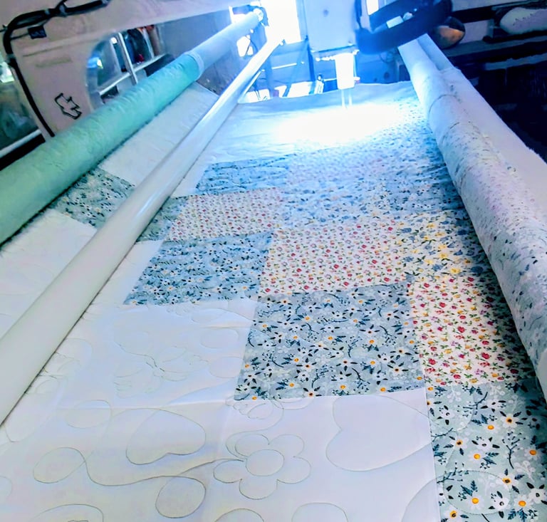 Longarm quilting machine stitching floral and butterfly patterns on a colorful patchwork quilt top.
