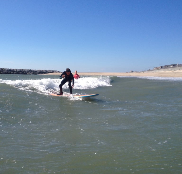 A young surfer riding a small unbroken wave in a surfing class