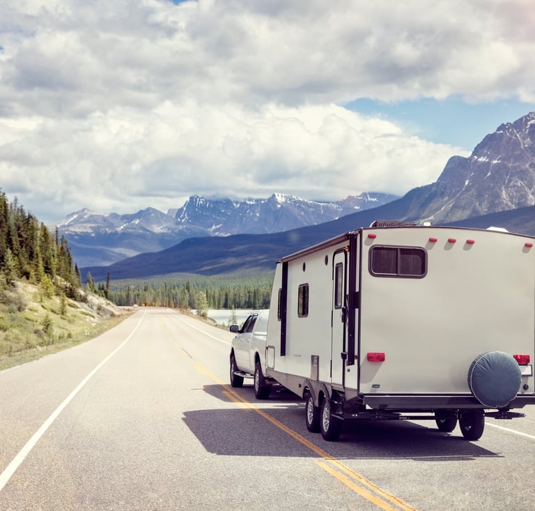 RV driving down road with mountains and trees.