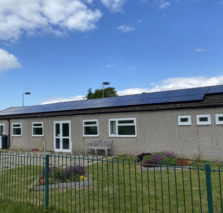 Elsenham Memorial Hall in Elsenham, exterior view with entrance doors, windows, bench seating and solar panels on the roof.