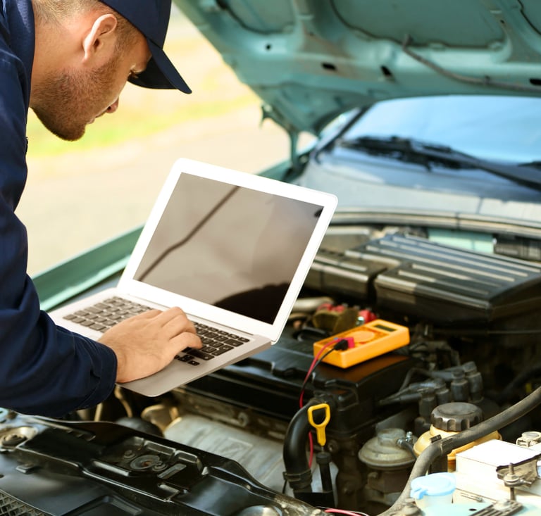 A professional mechanic uses a laptop to perform a digital car engine diagnostic for vehicle repair.