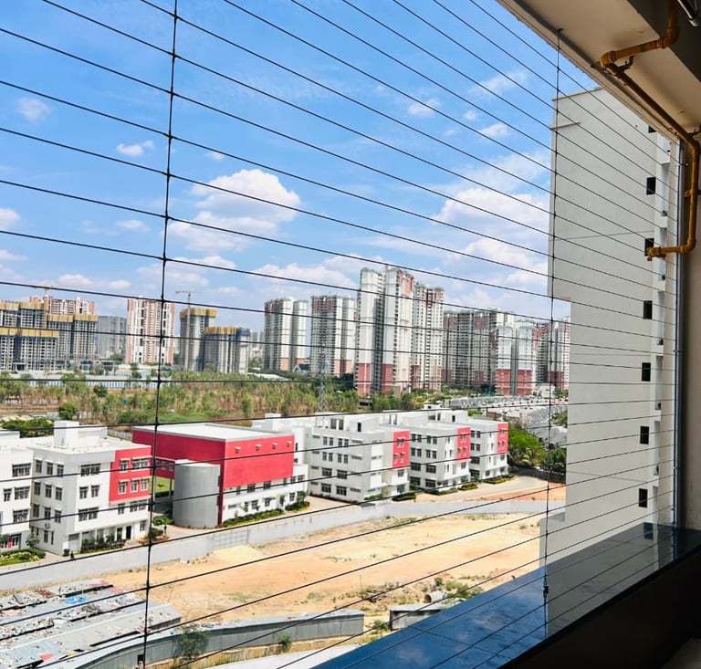 A professional installation of a balcony safety net in a modern high-rise in Hyderabad. The net is t