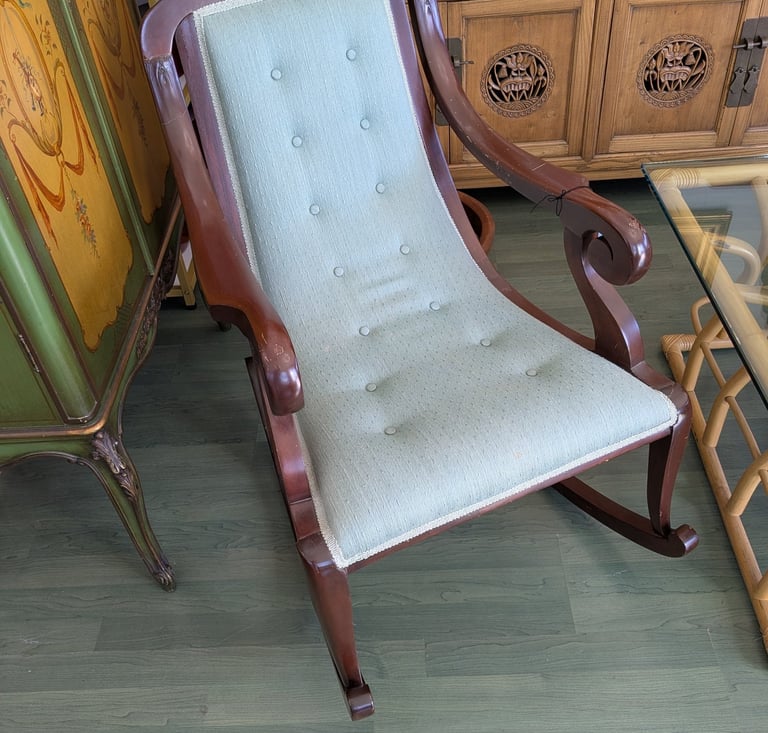 Vintage mahogany rocking chair with a tufted sage green upholstered seat and backrest.