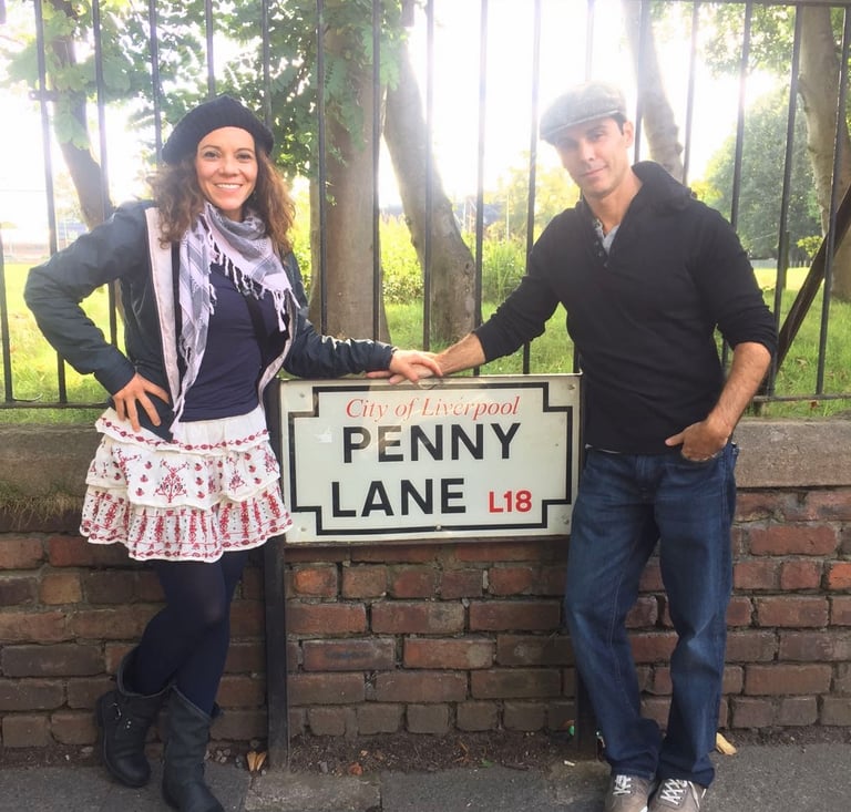 Couple standing in front of Penny Lane street sign in Liverpool England from Beatles song