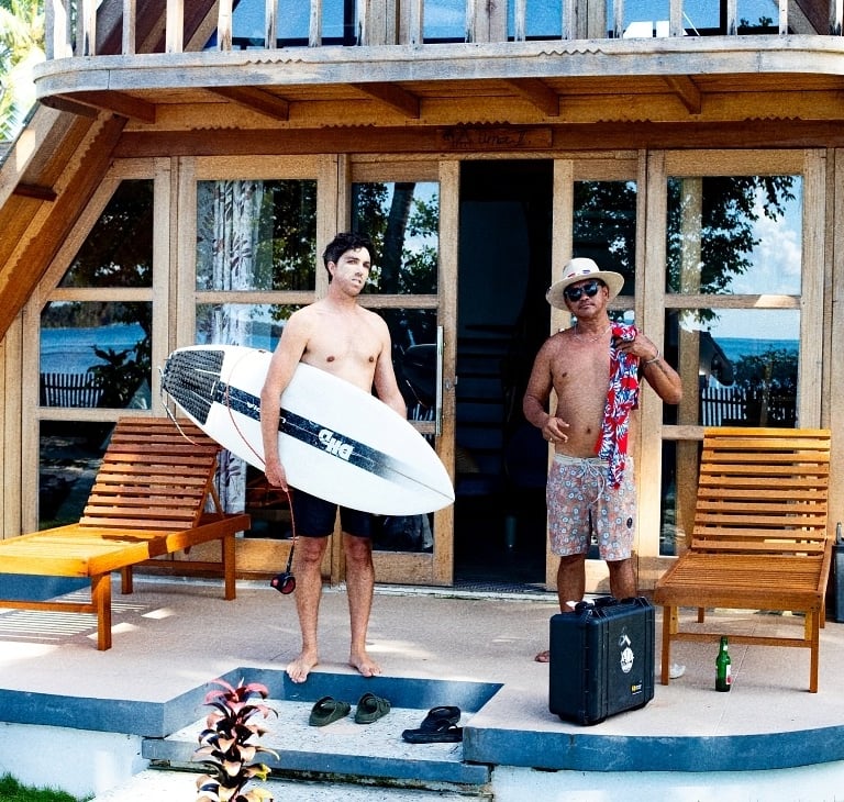 a man standing on a porch with a surfboard