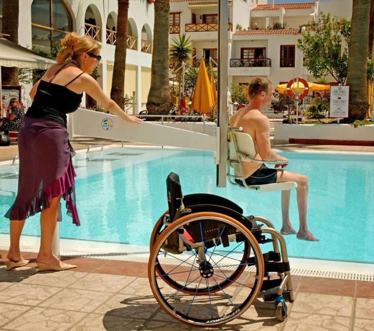 woman in wheelchair using a handicap lift at the swimming pool