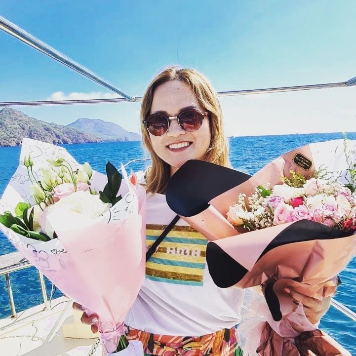 an asian woman holding a bunch of flowers on a boat