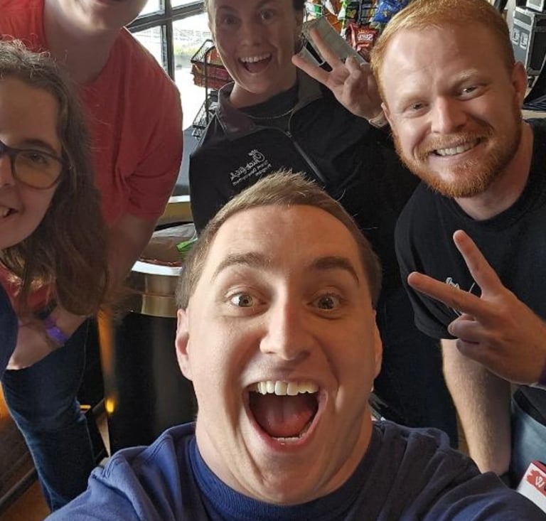 A group of happy coworkers taking a group selfie together during a TeamLab by WorkPlay Solutions
