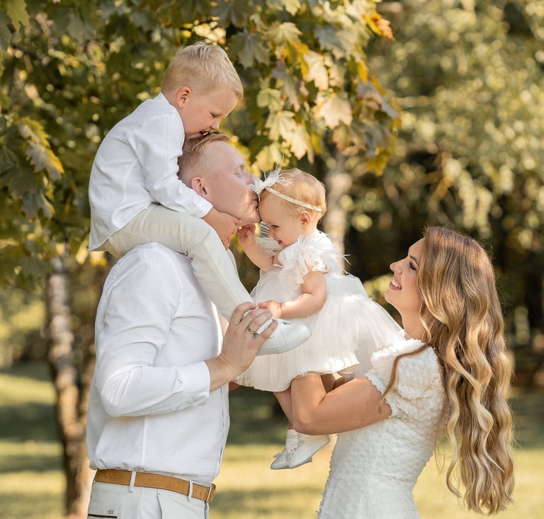 a man and woman holding a baby in a park