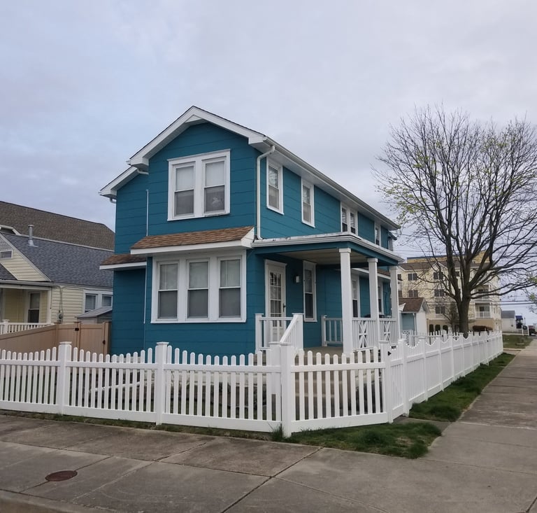 a blue house with a white picketd fenced in front of it