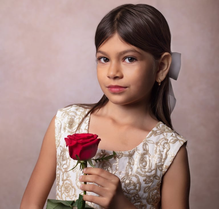 una niña mirando a la camara con una rosa roja en la mano