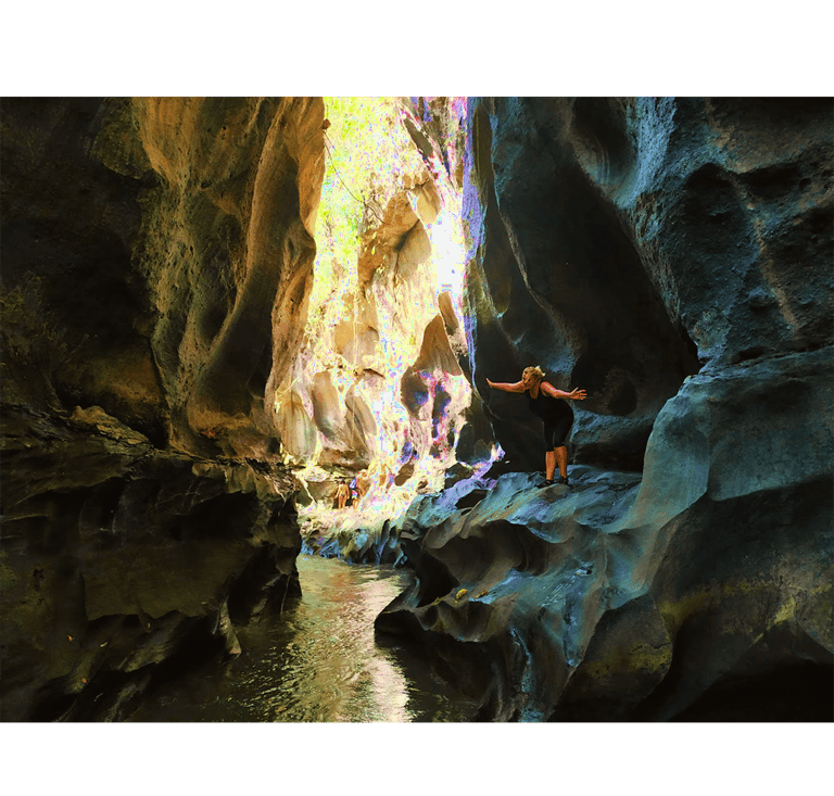 a person standing in a cave in a canyon