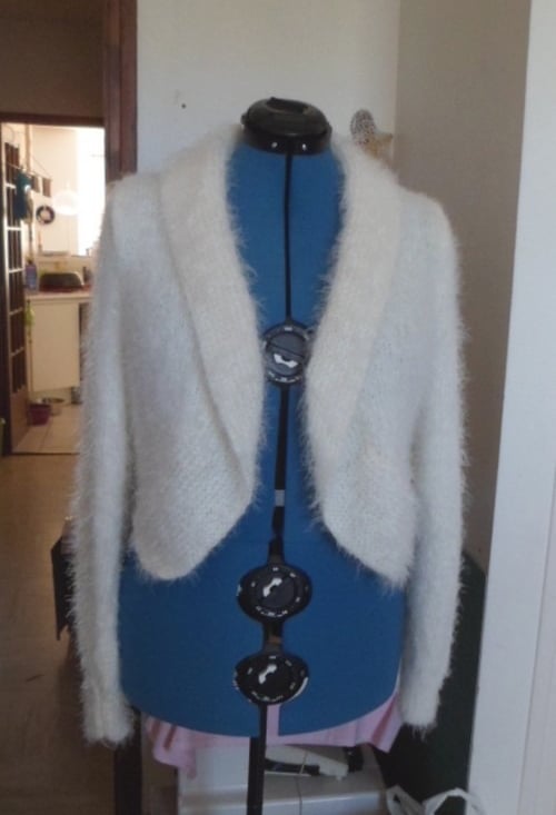 Modèle unique d'une veste tricoté à la main dans un fil couleur crème très doux