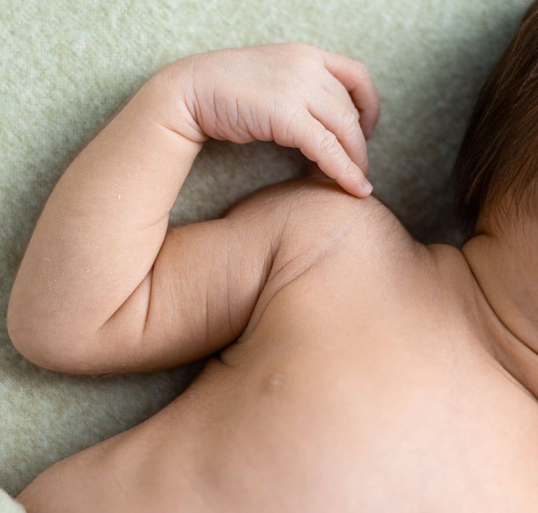 Detall de mans i cos d'un bebè nounat en una sessió de fotos newborn a Girona en estudi fotogràfic