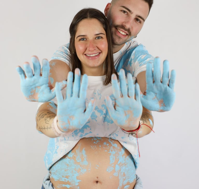 Sessió de fotos de gender reveal a Girona d'una parella amb pintura blava en estudi fotogràfic