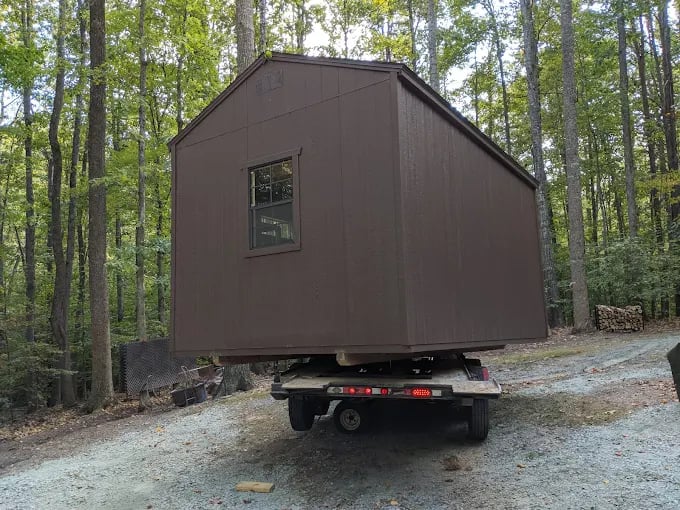 Shed being positioned for delivery with truck and trailer
