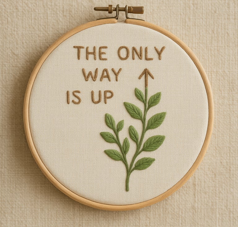 Embroidery hoop on a neutral background featuring the motivational phrase ‘The Only Way Is Up’