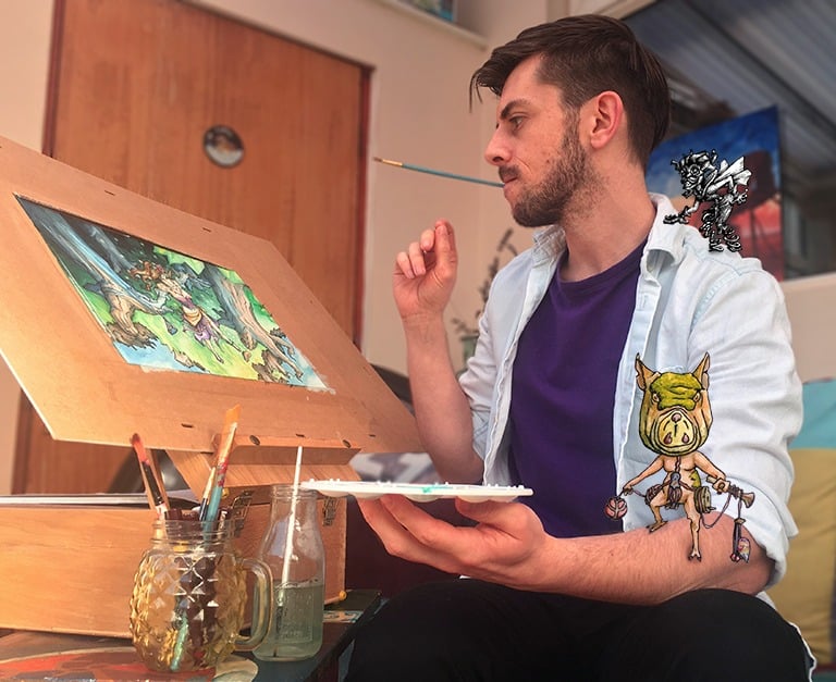 Handsome gay artist with a paintbrush in his mouth painting a fantasy art picture