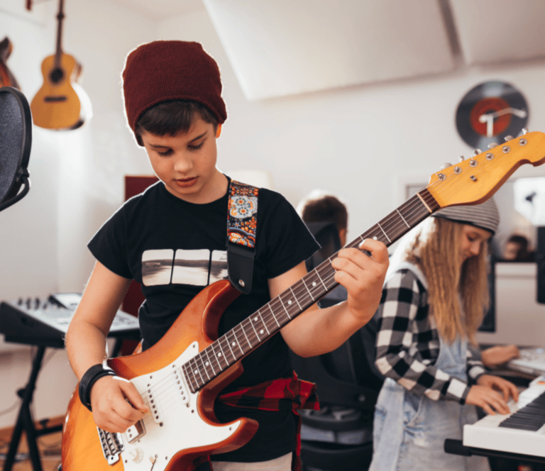 young boy playing guitar and young girl working sound tech in background