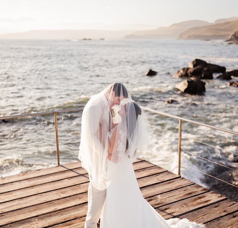 a bride and groom kissing on a pier