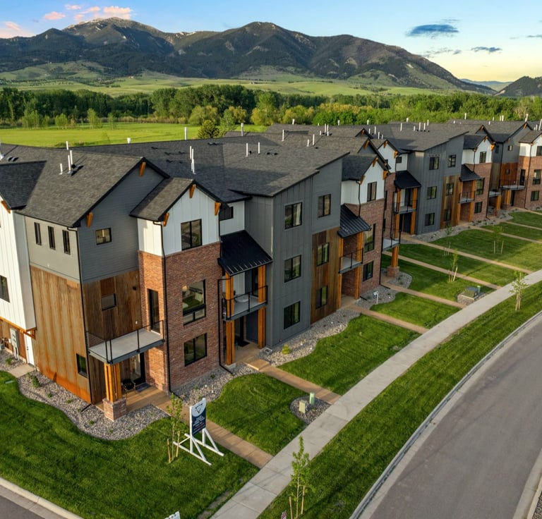 a large apartment complex with a lot of grass and a road