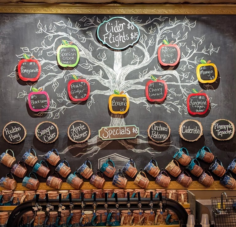 Rustic cider bar menu featuring cider flights, craft beer, and wine listed on chalkboard signs.