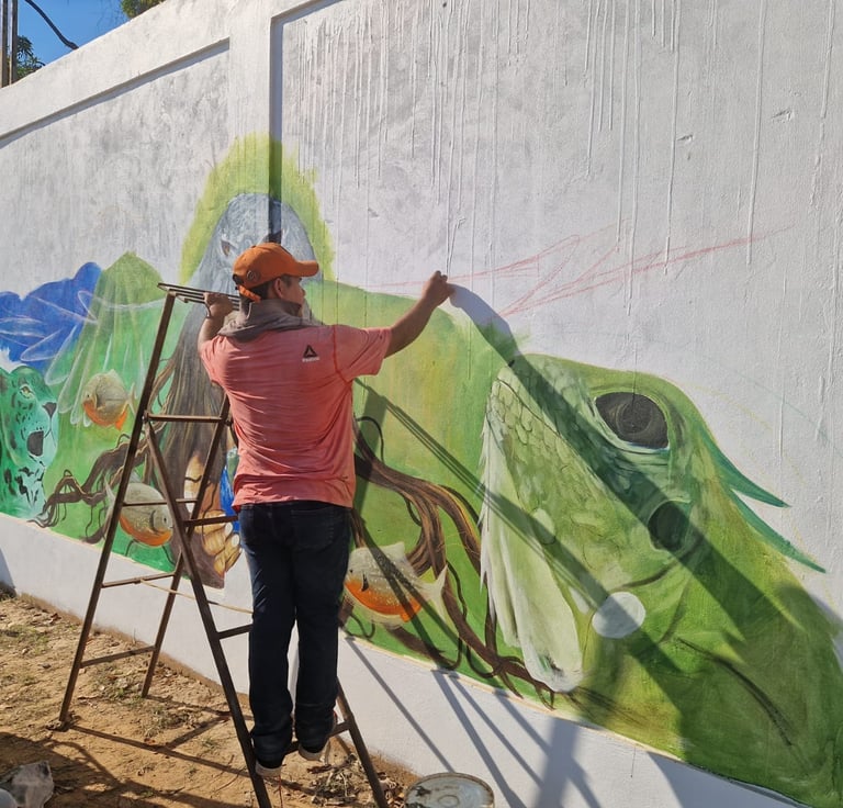 An artist on a ladder painting a colorful street mural at Centro Recreacional Mokanranko