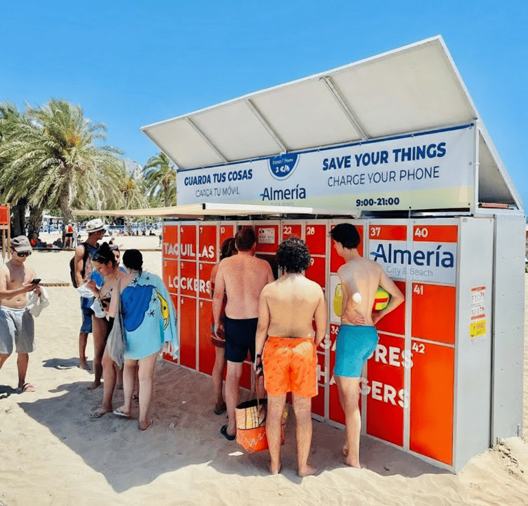 Piros színű strandszekrény előtt sorban állnak a strandolók