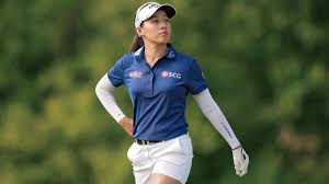 a woman in a blue shirt and white gloves playing golf
