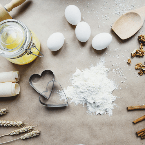 A cooking work table spread with eggs, rice, sticks of cinnamon, and two heart-shaped cookie cutters