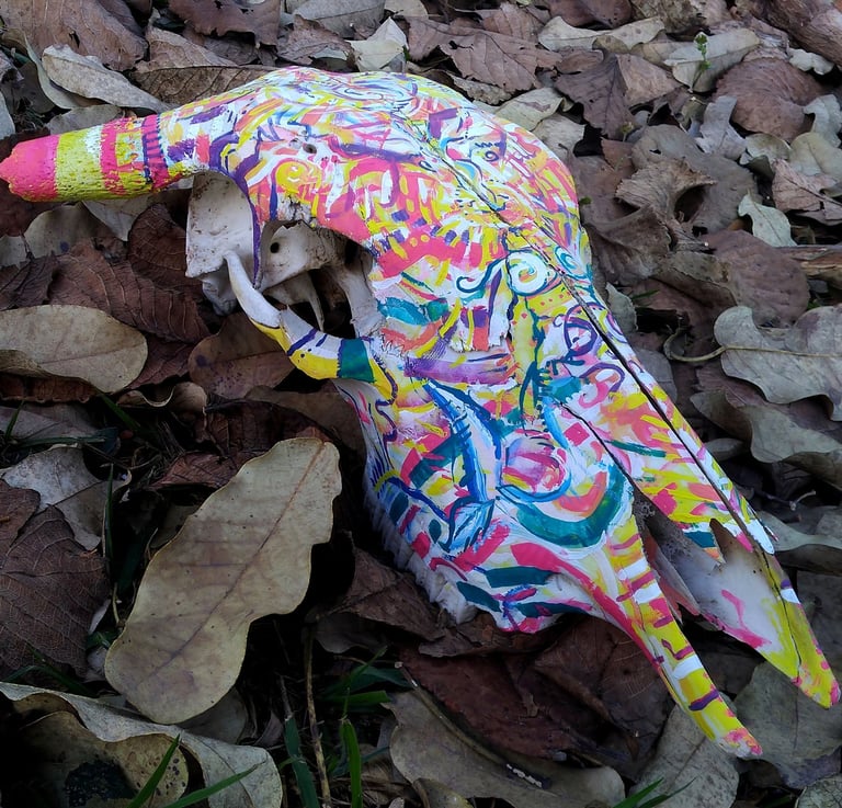 peinture aux couleurs vives sur un crane  sur un lit de feuilles mortes