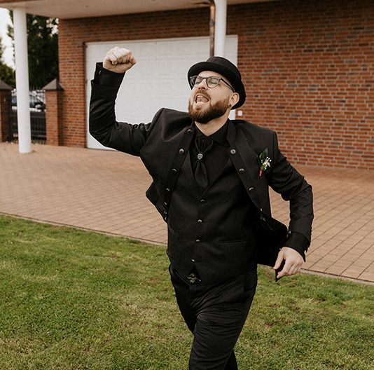 der Bräutigam im alternativen schwarzen Style feiert emotional seinen eigenen Einzug
