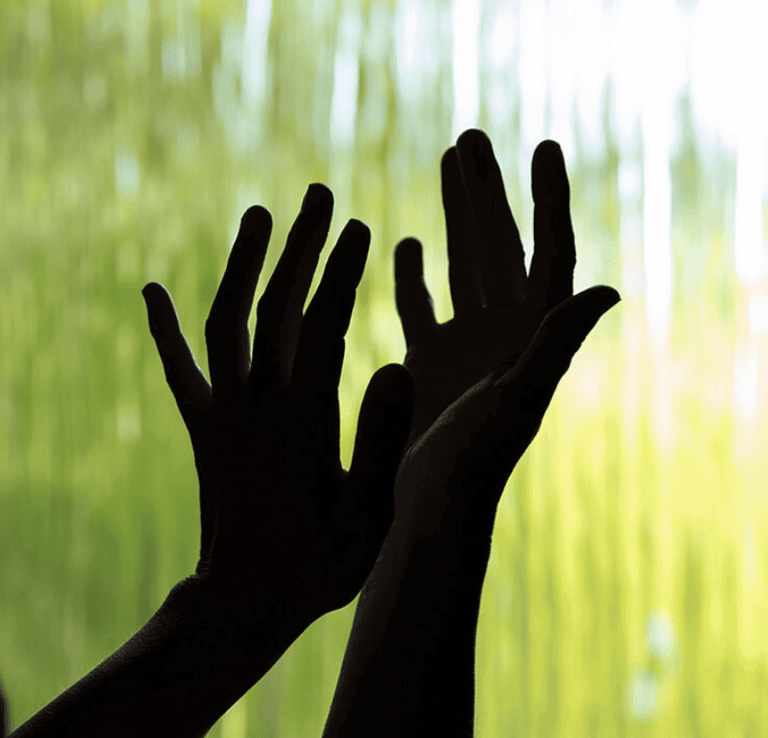 a person holding their hands up to a waterfall