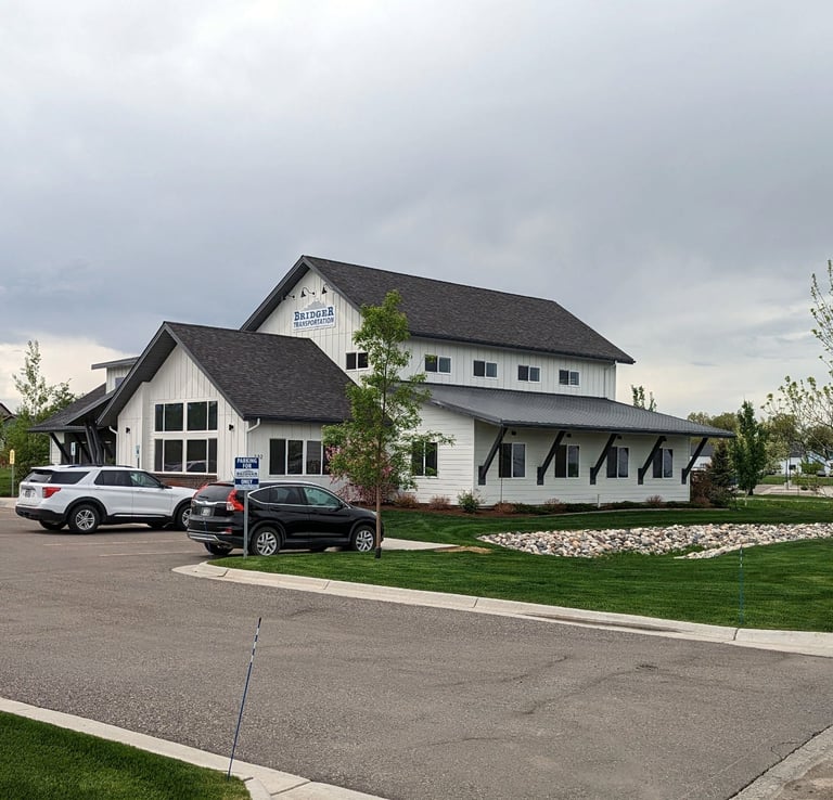 a white house with a black roof and a white car parked in front of it