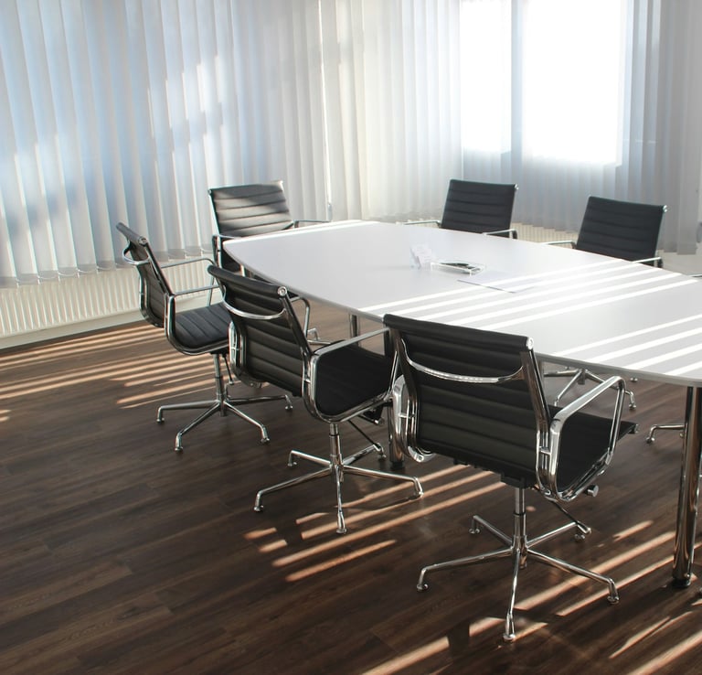 Modern meeting room with white conference table and black chairs 