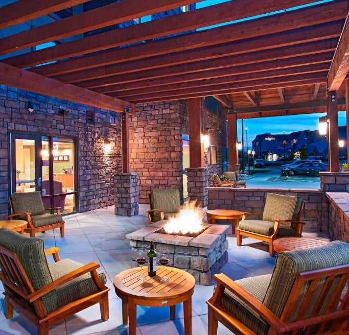 a patio with a fire pit and chairs