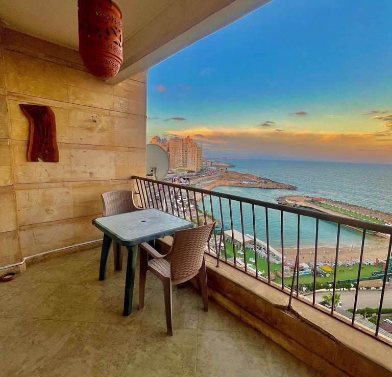 Luxury balcony view of a Mediterranean sunset over an Alexandria beach resort with outdoor seating.