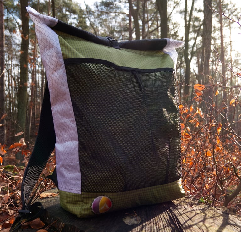 An ultralight backpack lying on the trunk, forest in the backgrond.