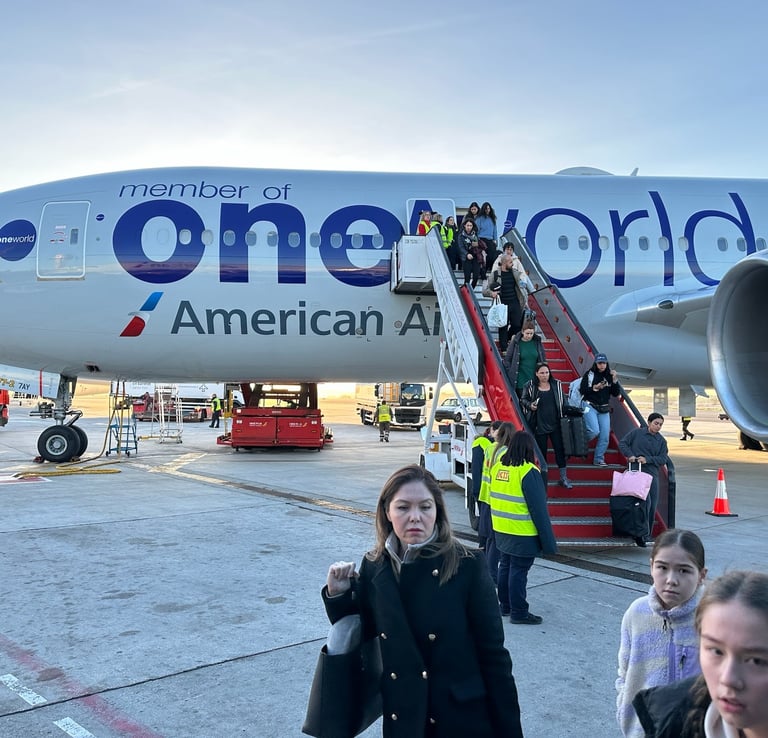 A silver Boeing 777 on the tarmac with a set of stairs pulled next to it