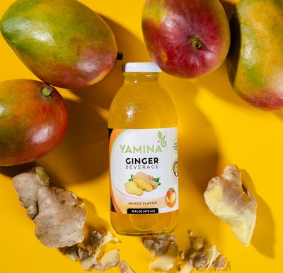 a bottle of ginger infused drink surrounded by mangos and ginger