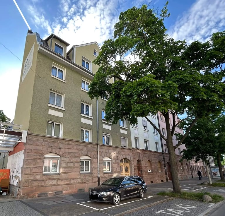 Mehrfamilienhaus mit grün-beiger Fassade und Sandstein im Erdgeschoss in Fürth-Ronhof.