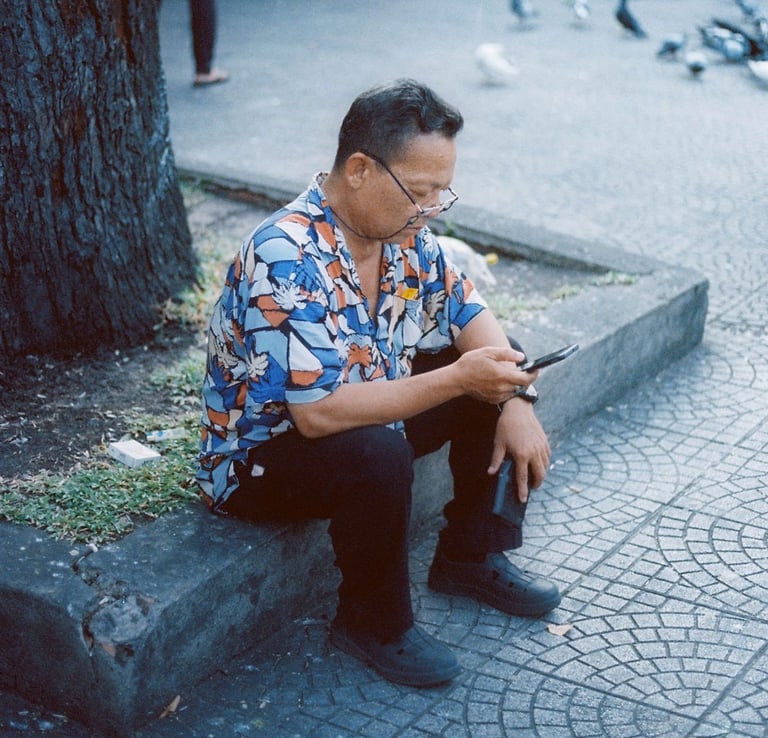 Vietnamese man checking the phone on the pavement in Saigon
