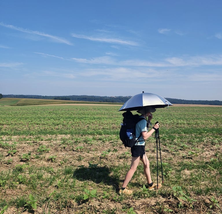 Woman hiking with an umbrella through field