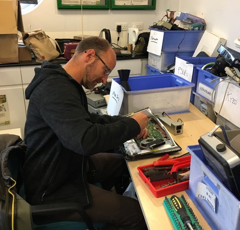 A Tech-Takeback technician works on a donated laptop