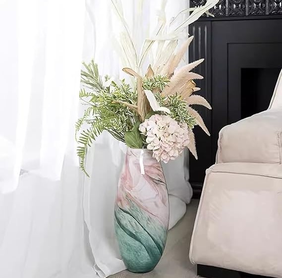 Tall gradient glass vase in soft pink and green tones with delicate white flowers.