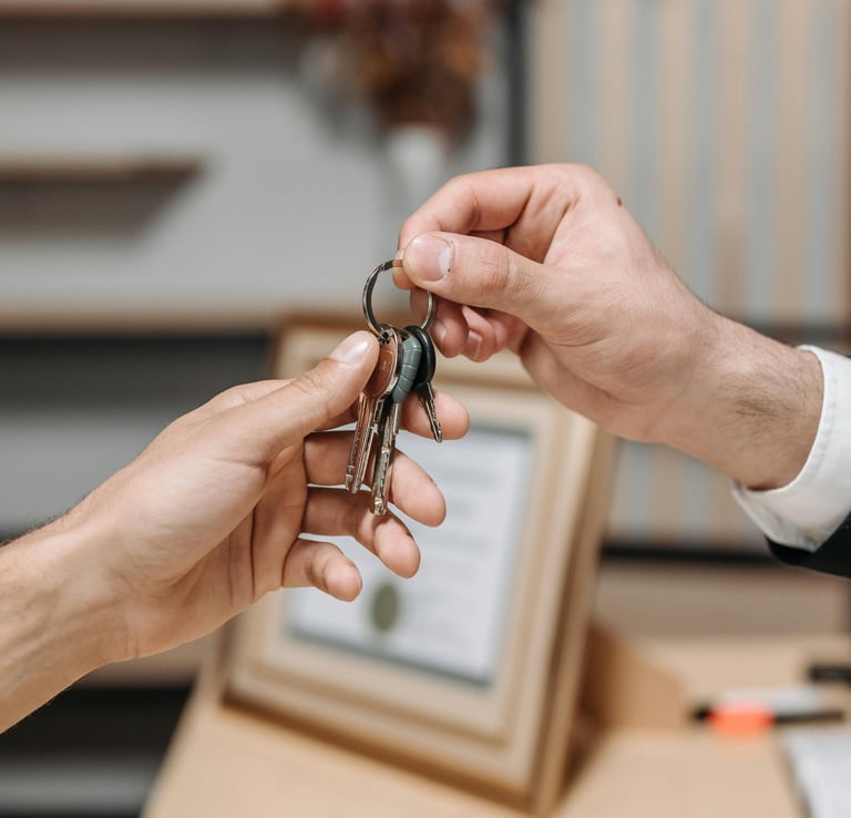 A real estate agent handing house keys to a new homeowner during a property closing.