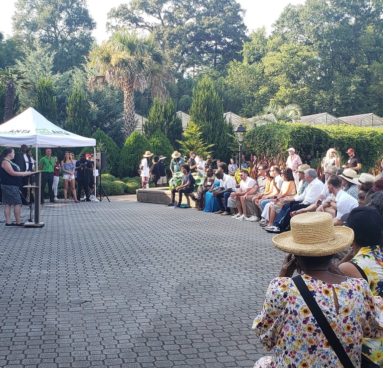 People gathered listening to speakers at the Atlanta Botanical Garden