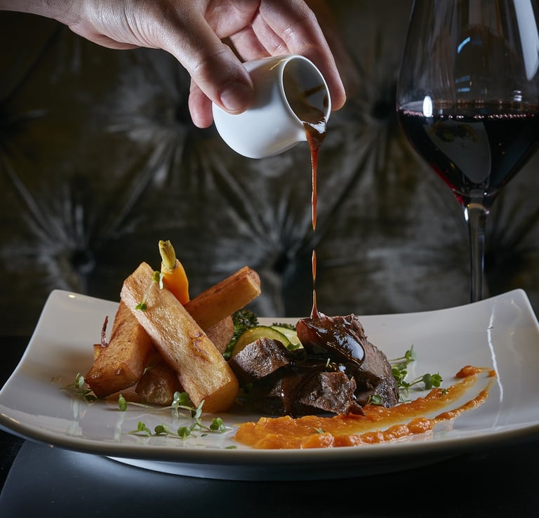 Gourmet Steak Dinner – Steak with sauce, fries, and red wine.