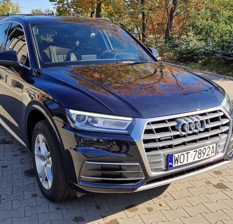 a black audi is parked on a brick road