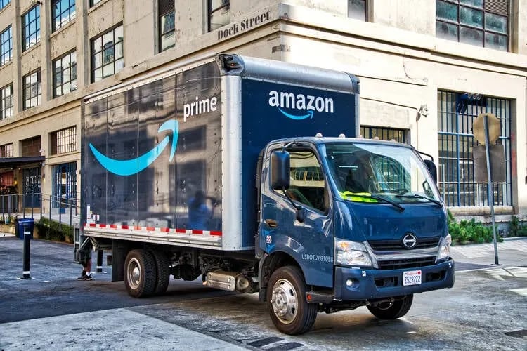 a truck with an amazon logo parked in front of a building
